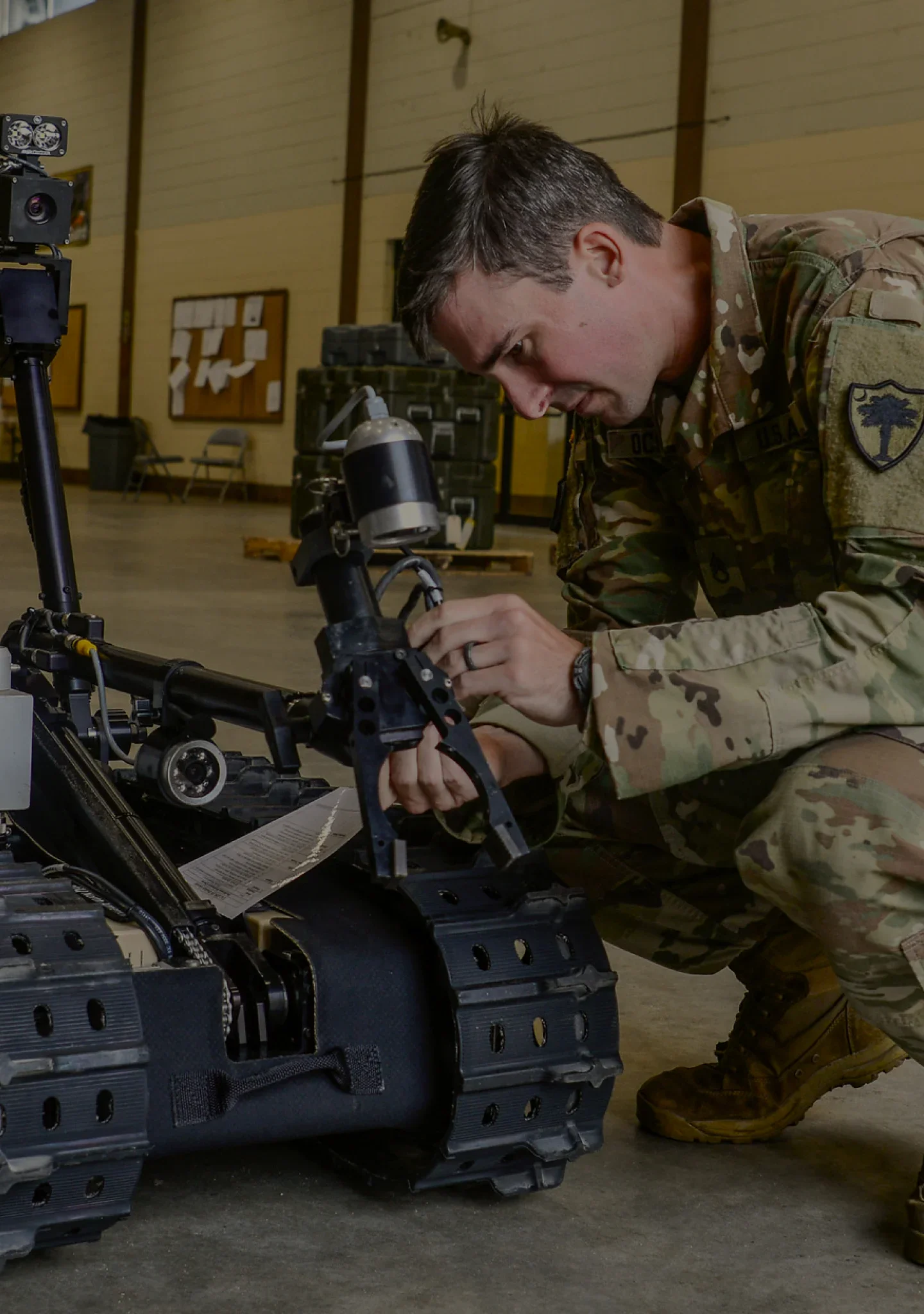 Un Ingeniero de Combate preparando un vehículo robótico para un entrenamiento de despeje de rutas