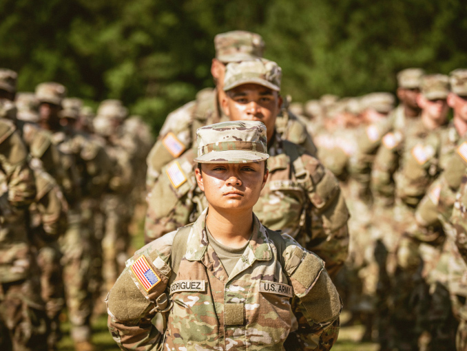 Multiple rows of Soldiers in combat uniform standing in formation outdoors