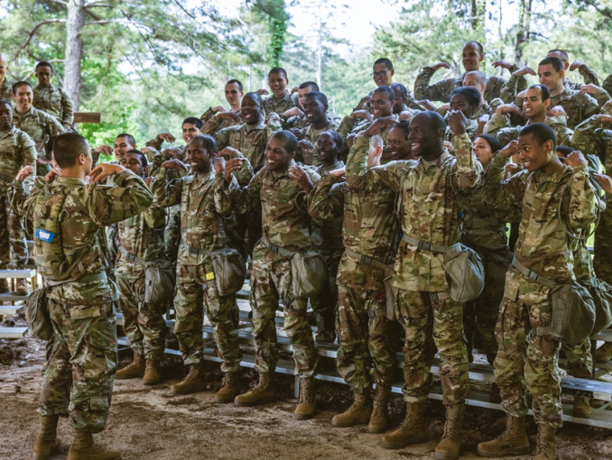 A large group of basic trainees standing on rafters in a forest