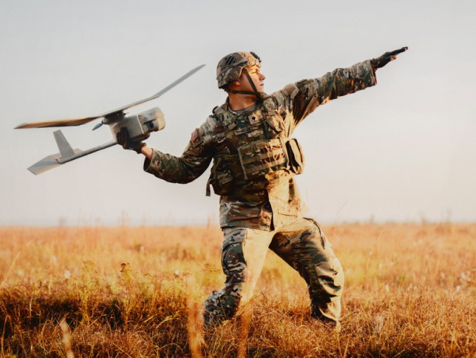 Un Soldado del Army en equipo de combate está de pie lanzando un dron