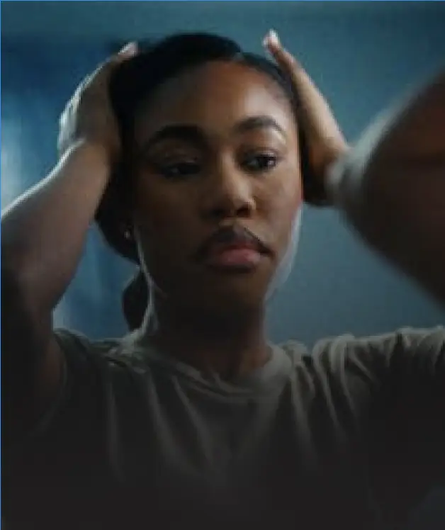A young woman in a tee shirt with her hands on her head