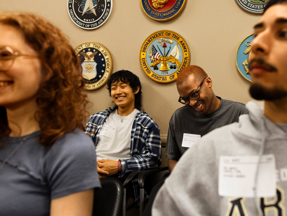 Two enlisted recruits sitting down and smiling at a Military Entrance Processing Station (MEPS)