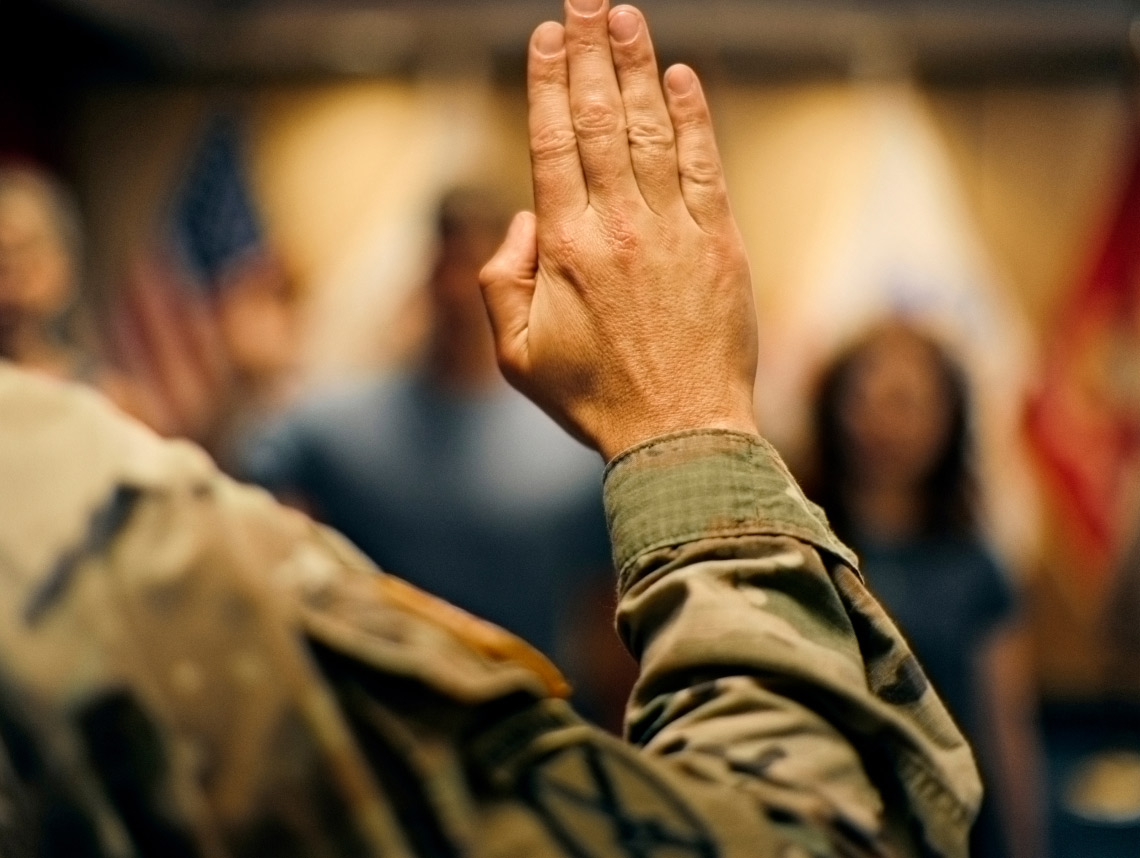 Light-skinned hand raised in the air taking the Oath of Enlistment