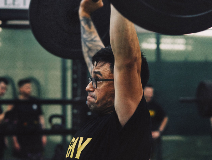 Un Soldado con una camiseta del Army levantando pesas en un gimnasio