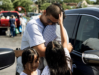 Family standing next to a black car and embracing each other