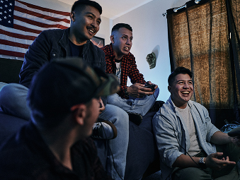 Four Soldiers out of uniform sitting in front of a TV playing video games