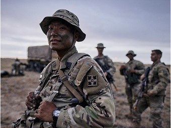 Soldier in uniform soft smiling with three other Soldiers in uniform standing in the background