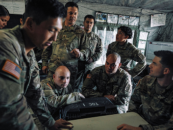 Seven male Soldiers sitting and strategizing together