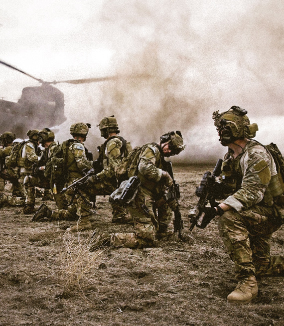 Fila de Soldados arrodillados en un campo con un helicóptero sobrevolando