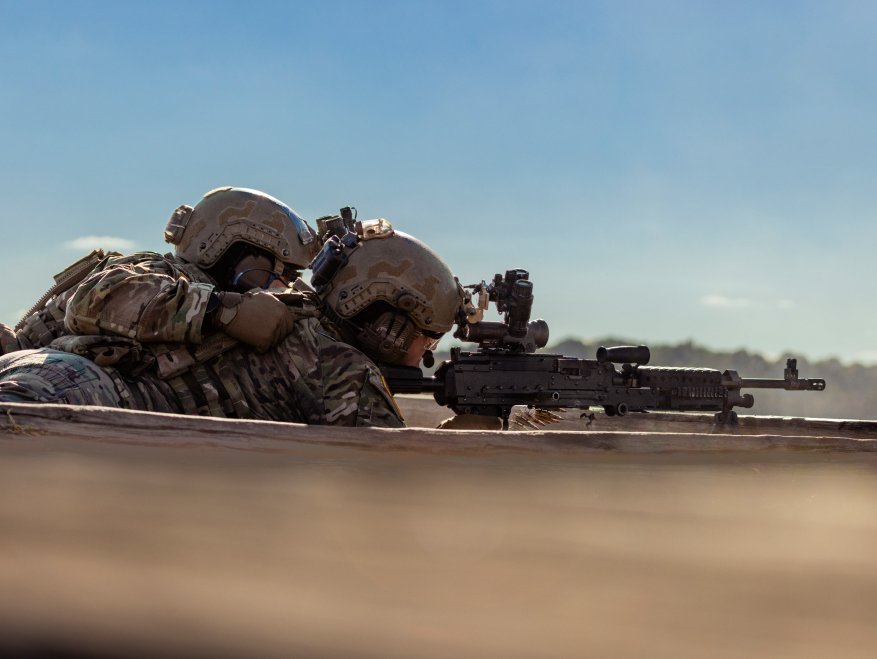 Two Soldiers crouching down in a forest and staring upwards