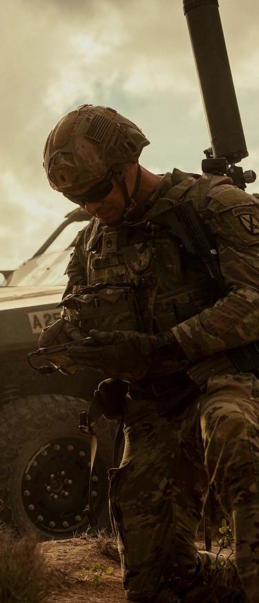 Soldados revisando equipo al lado de un vehículo militar