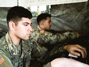 Male Soldier sitting down in uniform with his hands on a computer keyboard