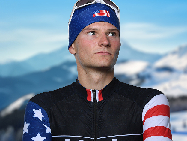 Sergeant Benjamin Loomis in a black, red, white, and blue USA ski uniform, crossing arms looking to the side with snowy mountains in the background