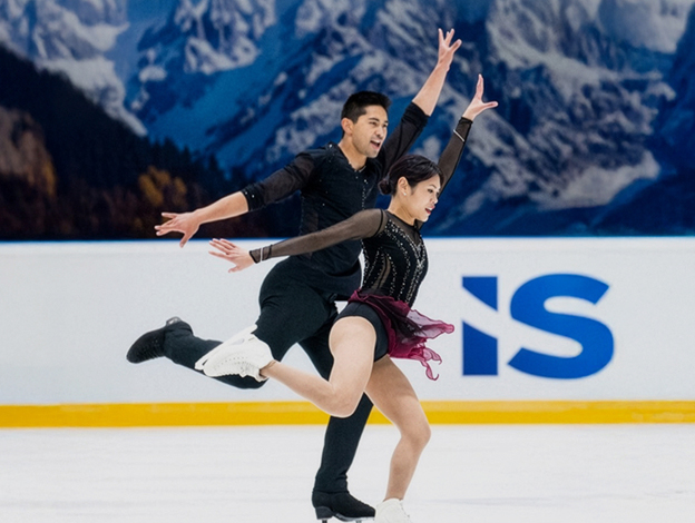 Pfc. Spencer Howe in a black outfit performing on ice with his figure skating partner, Emily Chan