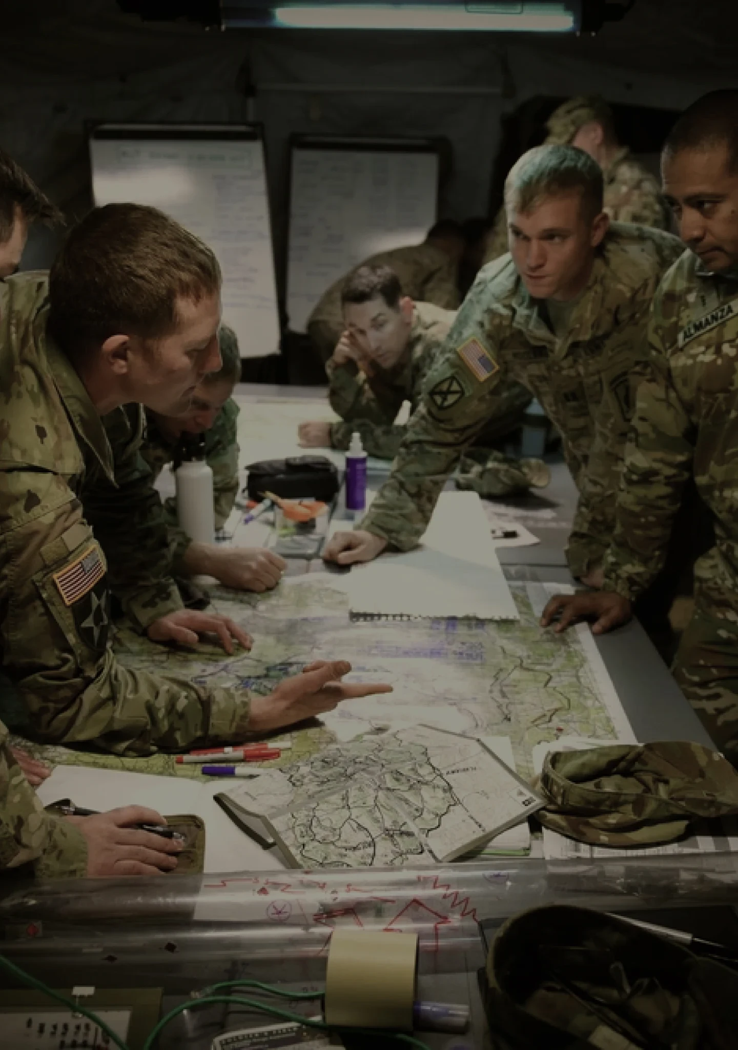 Un grupo de Soldados reunidos alrededor de una mesa examinando mapas
