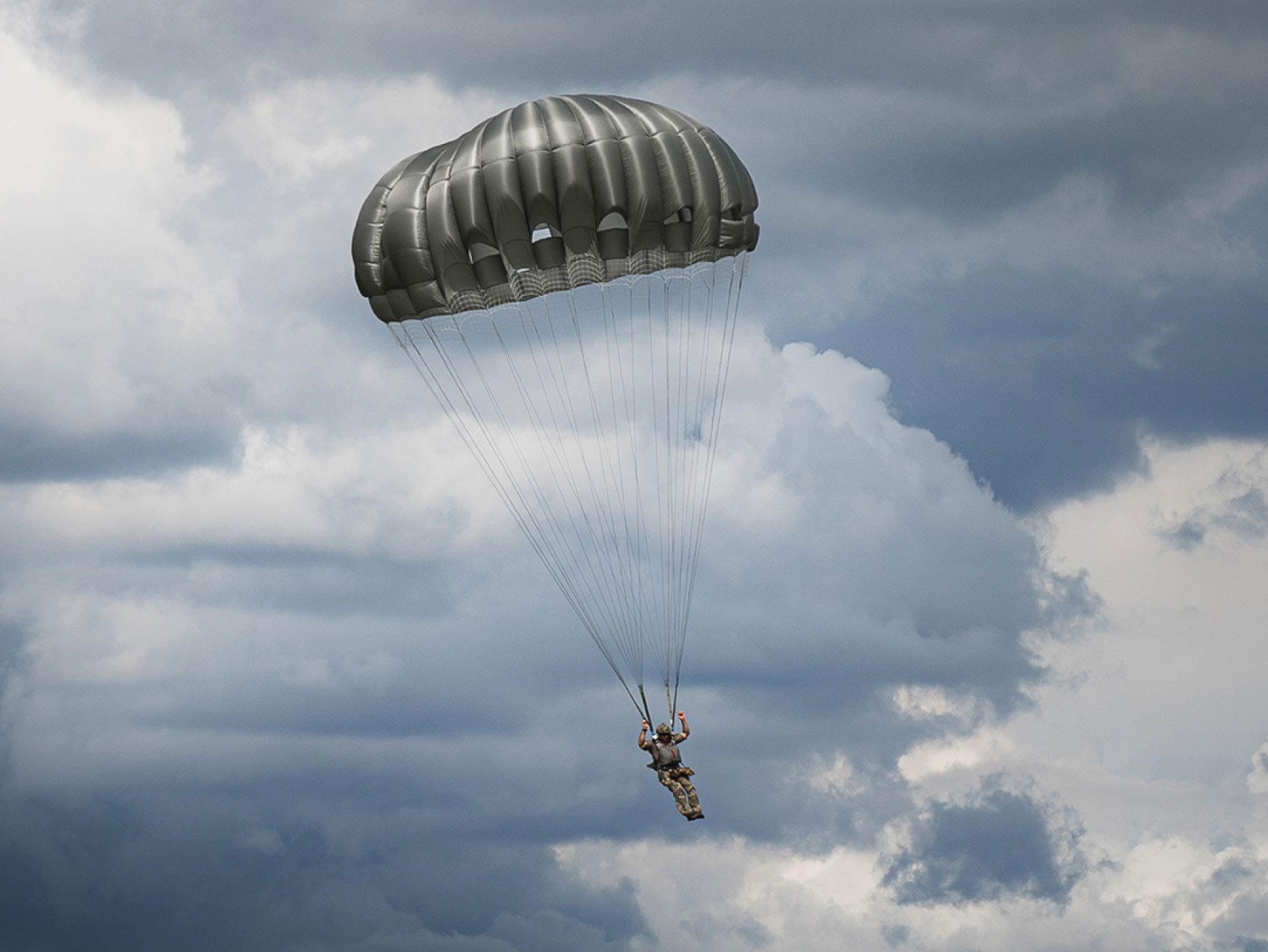 Army paratrooper parachuting during a cloudy day