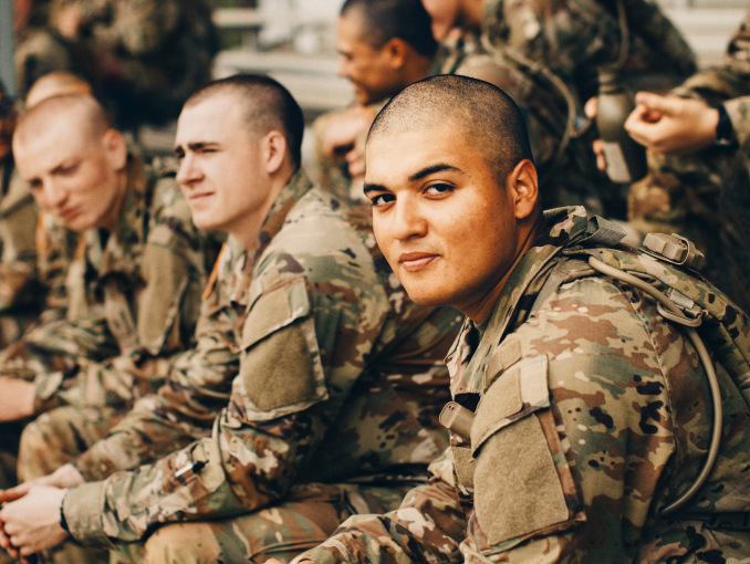 Soldiers in combat uniform sitting on bleachers