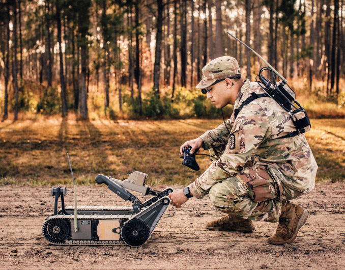 A Soldier preparing to operate a bomb disposal robot on a dirt road