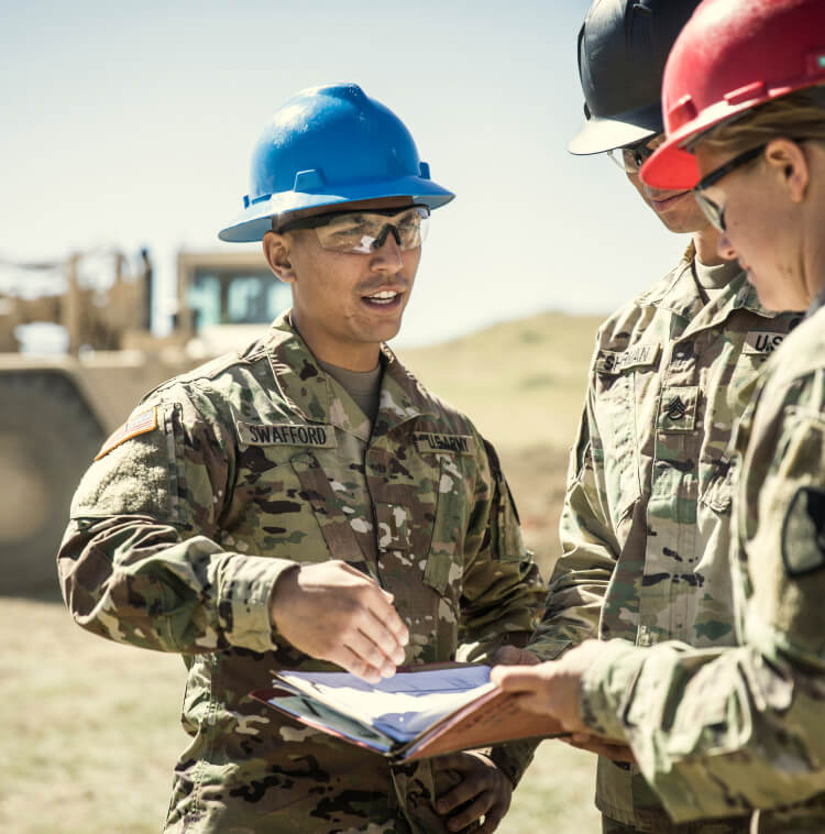 Three Army Soldiers reviewing blueprintson a construction site.