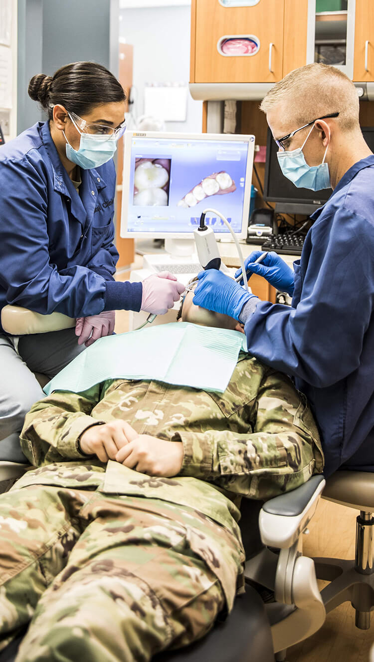 Two Army dentists performing a dental examination on a soldier.