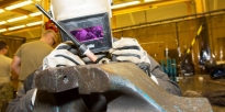 Soldier welds a tool designed to help replace a large fan assembly in a M88 track vehicle.