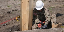 Soldier drilling into the foundation of a multipurpose building being built. 