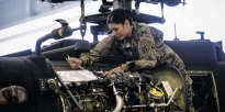 Soldier repairing a Apache helicopter inside a hangar.